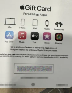 The image shows an Apple Gift Card, specifically designed for purchasing Apple products and services. The top section of the card displays the Apple logo followed by the text "Gift Card" and "For all things Apple". Below this, a series of icons represent Apple products and services such as Mac, iPhone, iPad, Watch, Accessories, App Store, Music, TV+, iTunes, and Fitness+. The card instructs to visit a website for redemption and notes the card's usage for online and Apple Store purchases. A barcode and a series of obscured numbers (for security) are visible towards the bottom. The footer provides a customer service number and legal information, dated 2022, affirming Apple Inc.'s copyright.