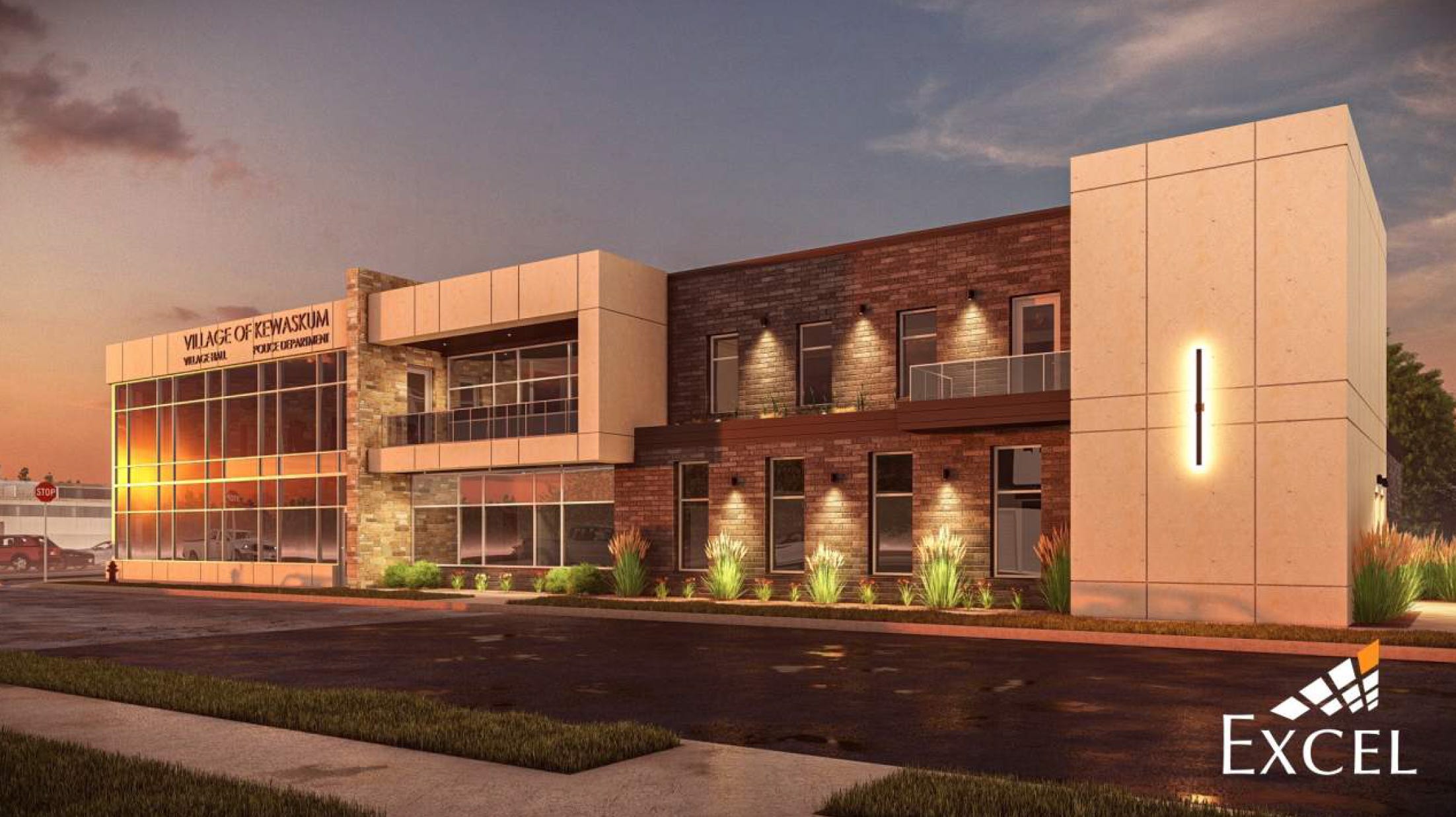 Architectural rendering of the proposed new Village of Kewaskum building. The modern, two-story brick and stone structure features large windows on both floors. Landscaping includes grass and small shrubs. The building is shown at dusk, with interior and exterior lighting illuminating the space. The "Village of Kewaskum" signage is prominently displayed on the front facade.