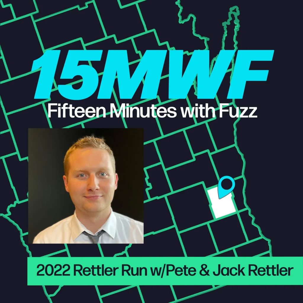A graphic for “Fifteen Minutes with Fuzz” features a background map outline in green on a dark blue background. The title “15MWF” in large teal letters is at the top, with “Fifteen Minutes with Fuzz” in white letters underneath. Below the title, there is an inset photo of a man with short blond hair, wearing a white shirt and smiling at the camera against a black background. At the bottom, a green label reads “2022 Rettler Run w/Pete & Jack Rettler.”