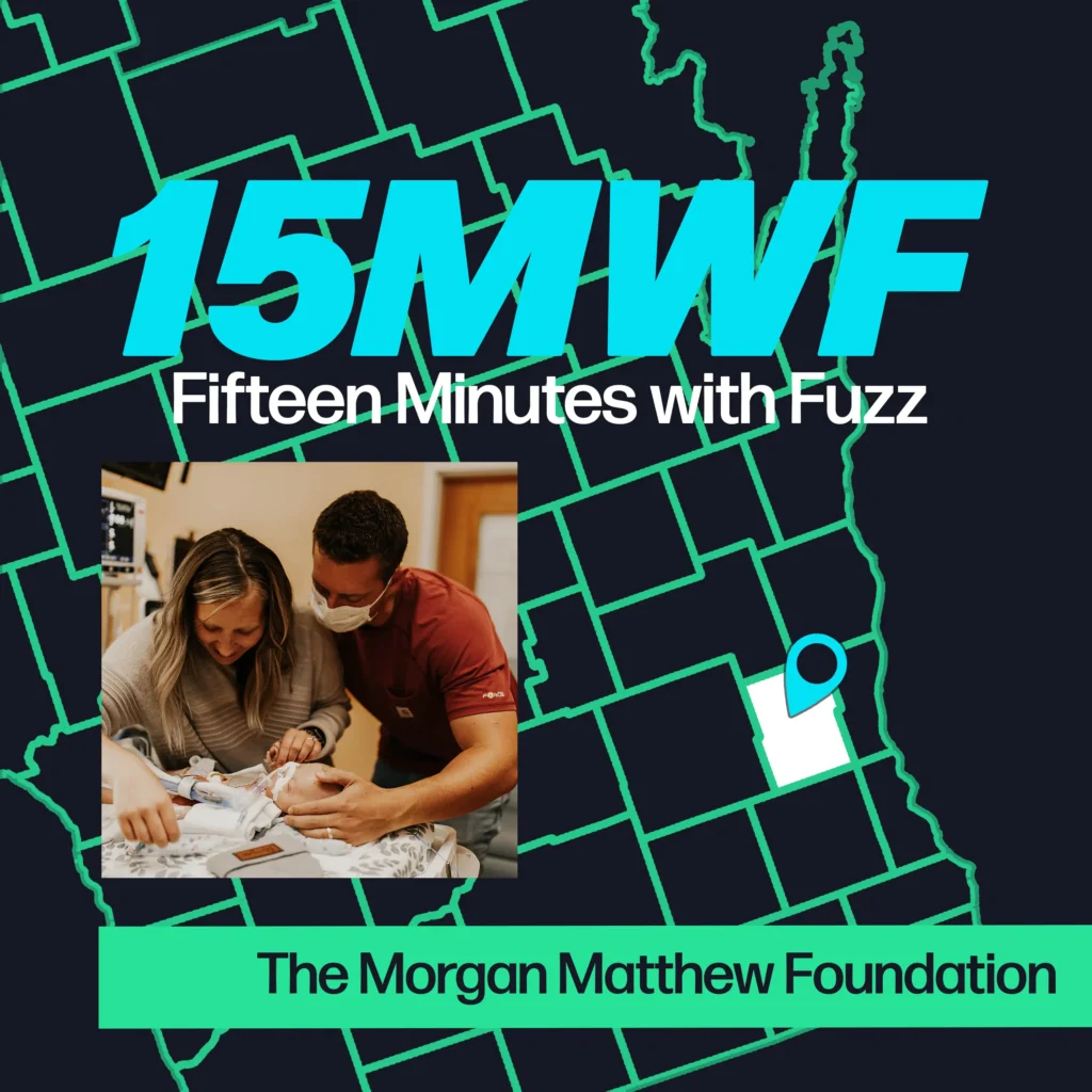 A graphic for “Fifteen Minutes with Fuzz” features a background map outline in green on a dark blue background. The title “15MWF” in large teal letters is at the top, with “Fifteen Minutes with Fuzz” in white letters underneath. Below the title, there is an inset photo of a woman and a man wearing a mask, lovingly looking at a baby. At the bottom, a green label reads “The Morgan Matthew Foundation.”