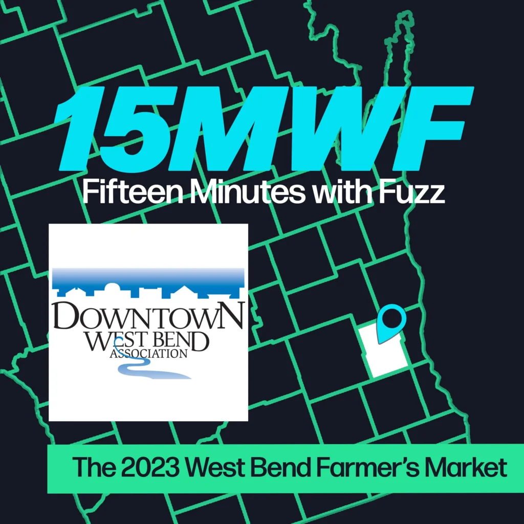 A graphic for “Fifteen Minutes with Fuzz” features a background map outline in green on a dark blue background. The title “15MWF” in large teal letters is at the top, with “Fifteen Minutes with Fuzz” in white letters underneath. Below the title, there is an inset photo of the Downtown West Bend Association logo, which includes a white background, a blue skyline, and the text “Downtown West Bend Association” with a small blue river graphic. At the bottom, a green label reads “The 2023 West Bend Farmer’s Market.”