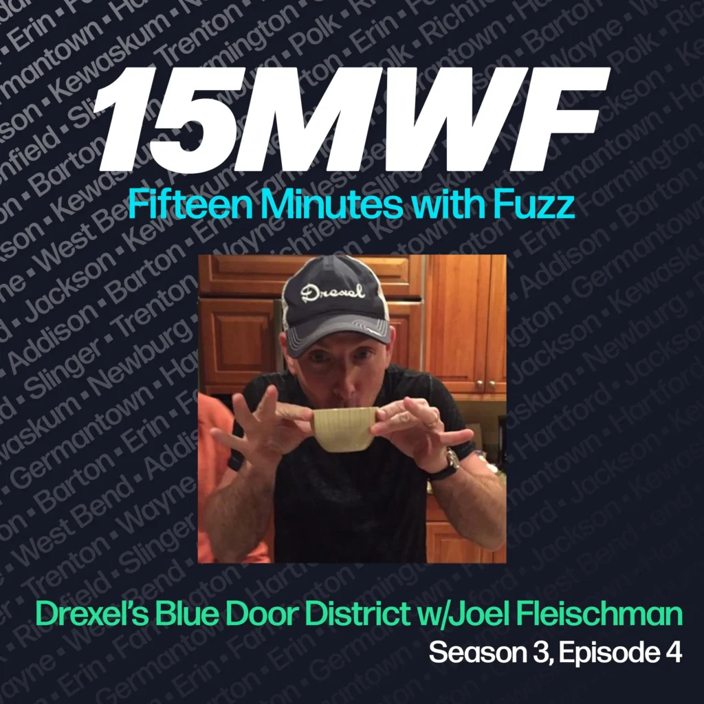 The cover art features a photo of Joel Fleischman, wearing a Drexel cap, sipping from a bowl, highlighting his approachable and down-to-earth personality. The podcast title “15MWF - Fifteen Minutes with Fuzz” is prominently displayed at the top. The background includes a pattern of names of different locations within Washington County, emphasizing the local focus of the podcast. The episode title “Drexel’s Blue Door District w/Joel Fleischman” is written at the bottom, along with the season and episode number.