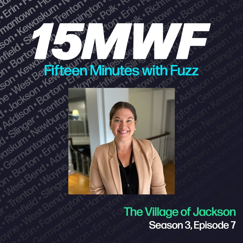 The cover art features a photo of a smiling woman in a beige blazer, emphasizing her professional involvement with the Village of Jackson. The podcast title “15MWF - Fifteen Minutes with Fuzz” is prominently displayed at the top. The background features a pattern of names of different locations within Washington County, underscoring the local focus of the podcast. The episode title “The Village of Jackson” is written at the bottom, along with the season and episode number.