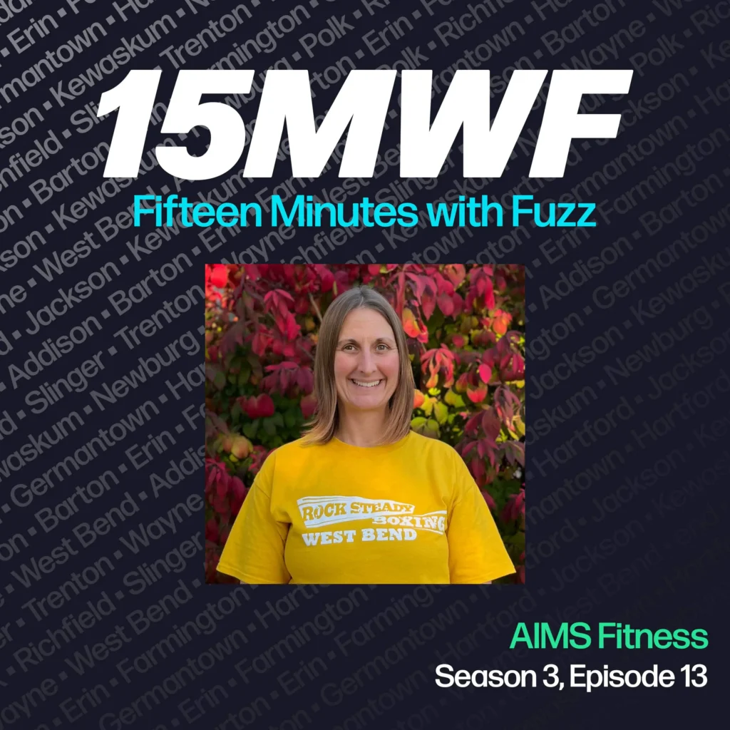 15MWF - Fifteen Minutes with Fuzz podcast cover art for Season 3, Episode 13 featuring a representative from AIMS Fitness. The background includes names of various locations within Washington County, emphasizing the local focus of the podcast. The guest is standing and smiling, wearing a ‘Rock Steady Boxing West Bend’ yellow t-shirt, with colorful foliage in the background.