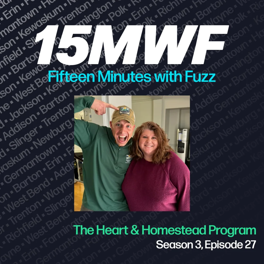 15MWF - Fifteen Minutes with Fuzz podcast cover art for Season 3, Episode 27 featuring The Heart & Homestead Program. The background includes names of various locations within Washington County, emphasizing the local focus of the podcast. A photo of two people smiling, with one pointing at their hat and the other standing beside them, is placed in the center.