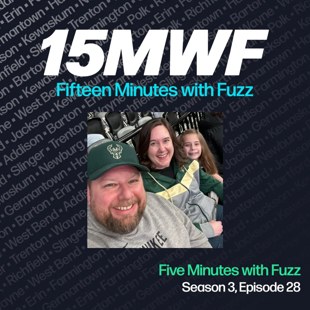 15MWF - Fifteen Minutes with Fuzz podcast cover art for Season 3, Episode 28 titled ‘Five Minutes with Fuzz.’ The background includes names of various locations within Washington County, emphasizing the local focus of the podcast. A photo of Fuzz Martin smiling with his family at a sports event, featuring him in a Milwaukee Bucks hat, is placed in the center.