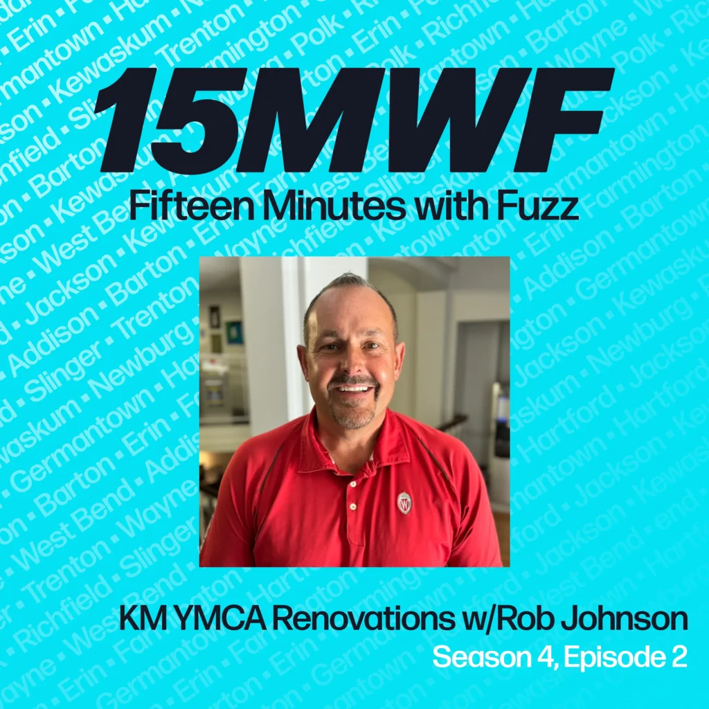 15MWF Fifteen Minutes with Fuzz. Kettle Moraine YMCA Renovations with Rob Johnson. Season 4, Episode 2. The image features a photo of Rob Johnson wearing a red shirt with a white logo, smiling, and standing indoors. The background includes various shades of blue with a pattern of location names (West Bend, Kewaskum, Slinger, Addison, Barton, Erin, etc.) and the podcast logo “15MWF” prominently displayed at the top.