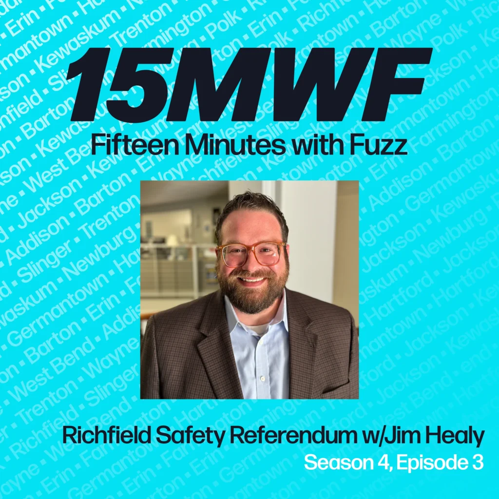 Podcast promotional image for ‘Fifteen Minutes with Fuzz,’ featuring a bright turquoise background with the names of various towns in a lighter blue font. The large text at the top reads ‘15MWF’ in bold black letters, and below it says ‘Fifteen Minutes with Fuzz’ in black. A photo of a smiling man with glasses, a beard, and wearing a brown jacket over a light blue shirt is positioned in the lower right. The bottom text reads ‘Richfield Safety Referendum w/Jim Healy, Season 4, Episode 3’ in black and white font.